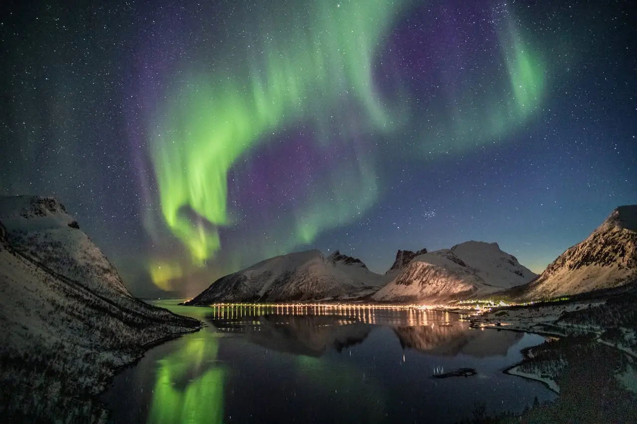 team-02 Stunning northern lights dance over snow-capped mountains reflecting in a tranquil lake at night.